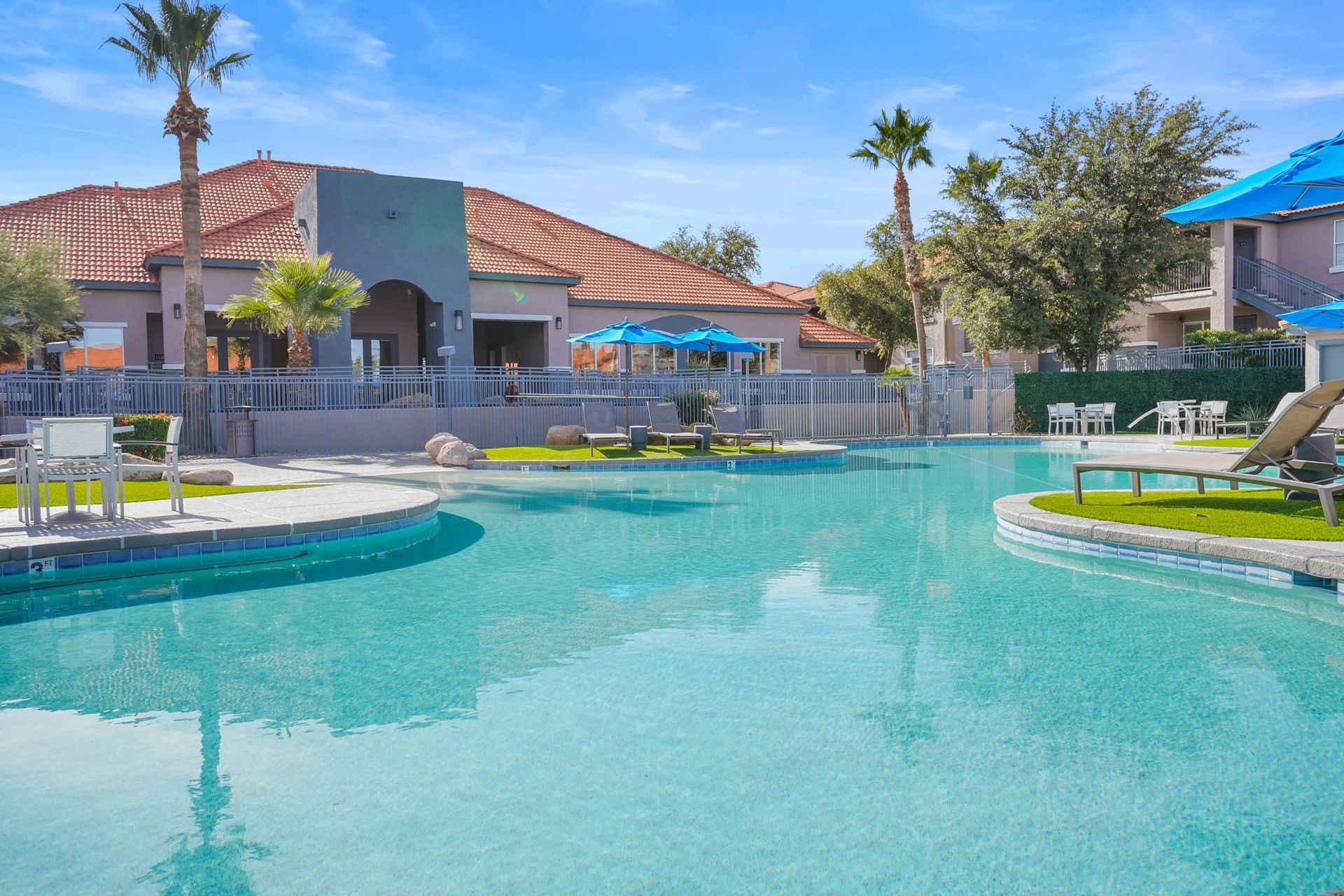 Outdoor pool at a multifamily community with lounge chairs and blue umbrellas.  Experience relaxed desert living by scheduling a tour of our comfortable apts in Tucson, AZ today.

