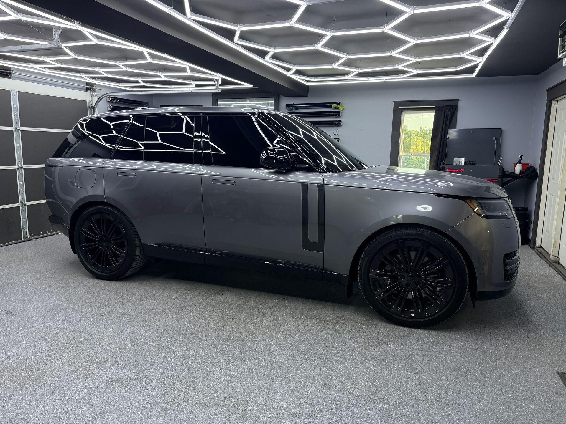 Gray luxury SUV parked in a modern garage with geometric ceiling lights