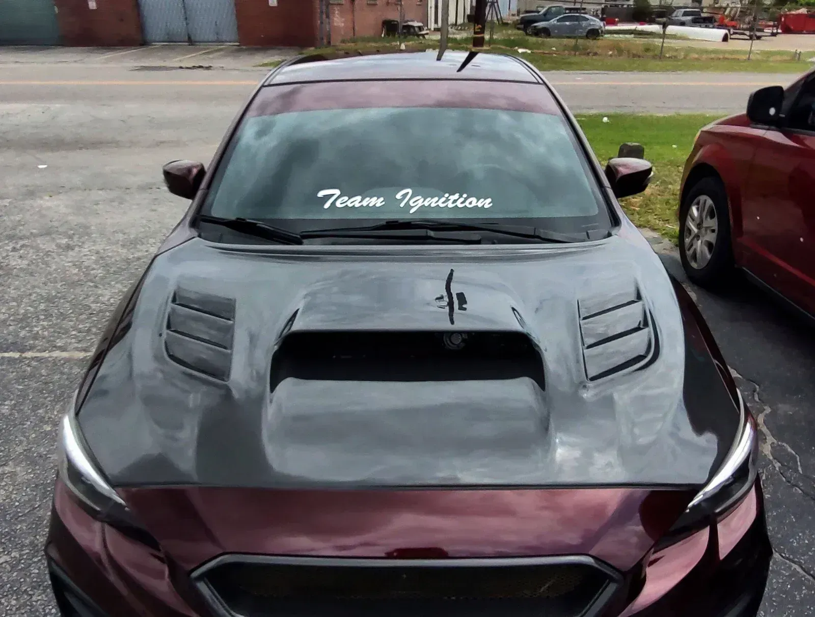 Dark red Subaru with a carbon fiber hood. 