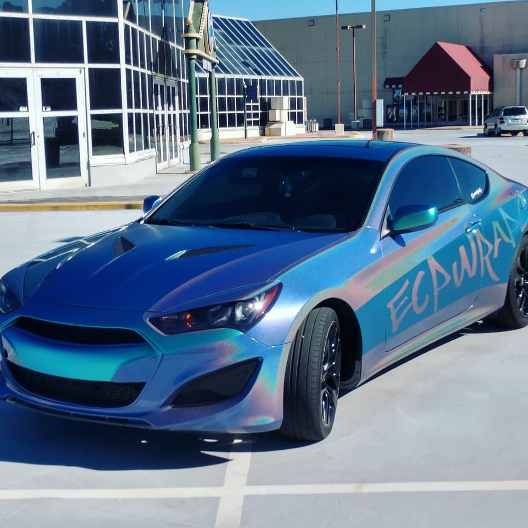 Blue iridescent wrapped car parked outdoors. 