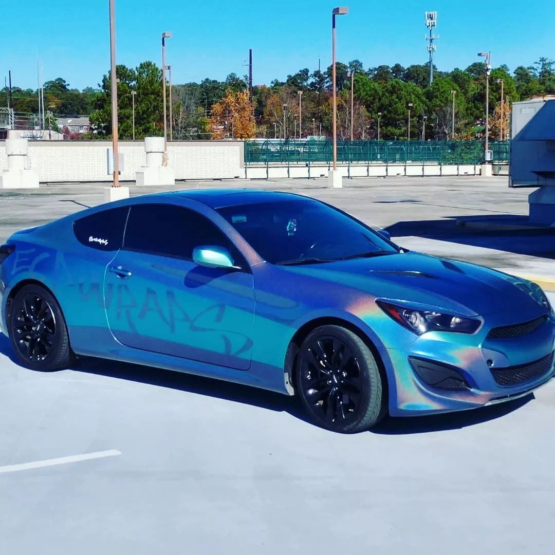Blue iridescent Hyundai Genesis coupe parked in a parking lot. Black rims.