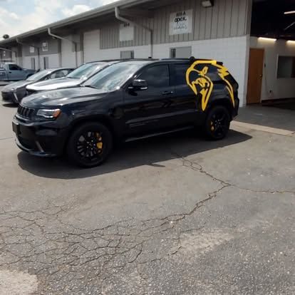 Black Jeep SUV with yellow graphic parked in front of a building.