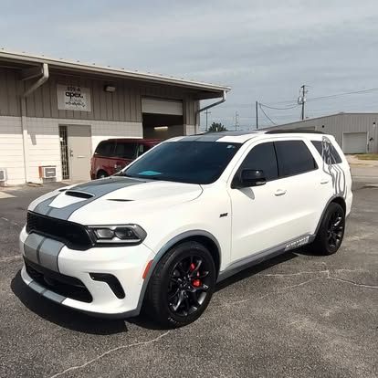White Dodge Durango SUV with gray racing stripes parked in front of a building.