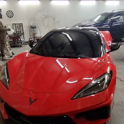 Red Corvette sports car with tinted windows in a garage.