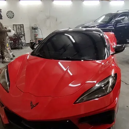Bright red Corvette in a garage with tinted windows.