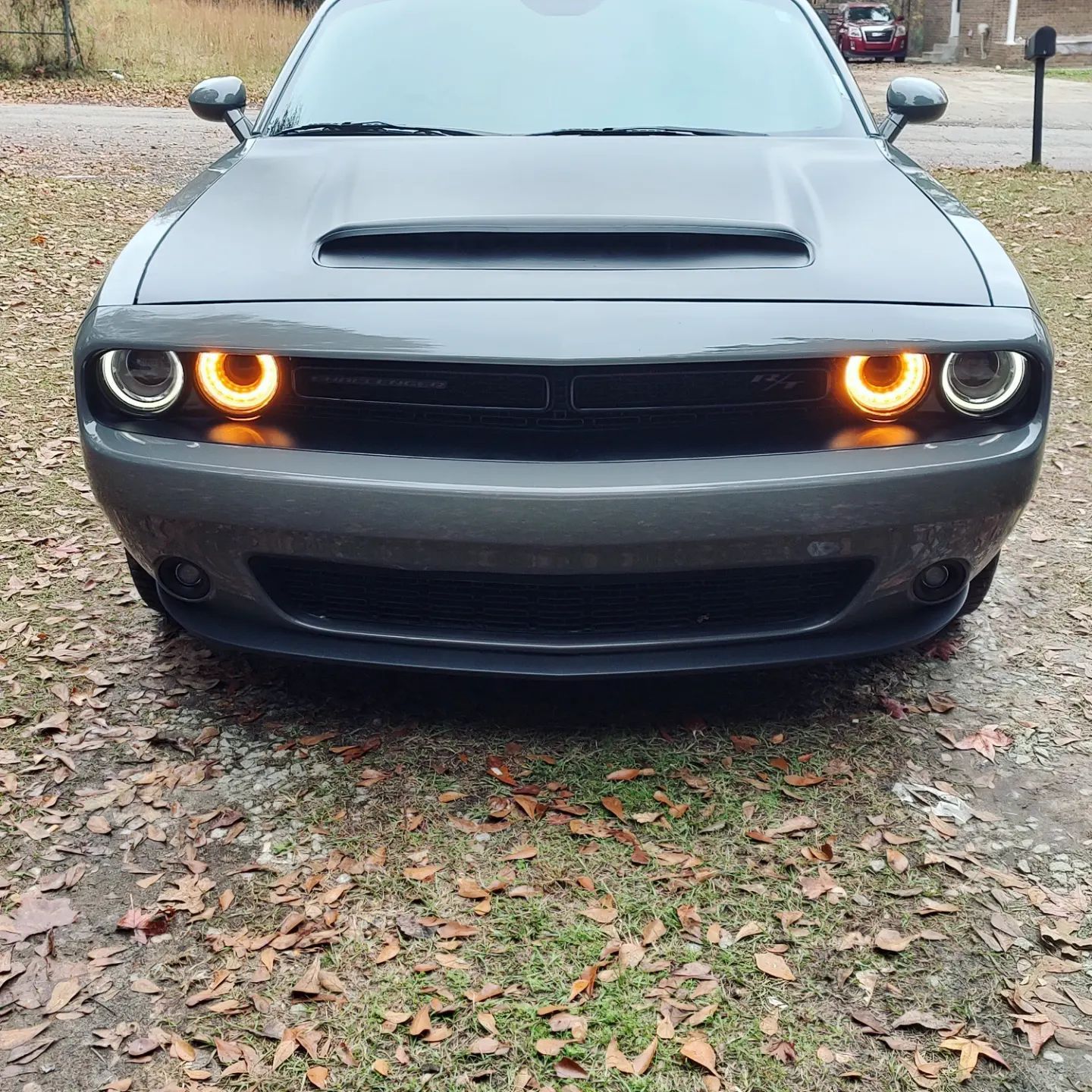 Dark gray Dodge Challenger with amber daytime running lights parked outside.