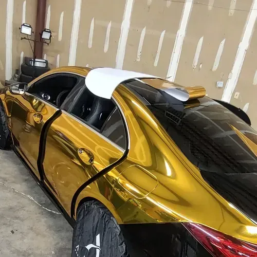 Gold and black car with a white spoiler in a garage.