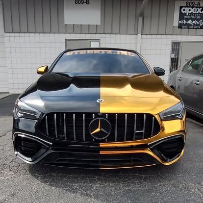 Split-color Mercedes-Benz AMG, black and gold, parked in front of a building.