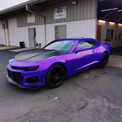 Purple Chevrolet Camaro with black hood and wheels parked in front of a building.