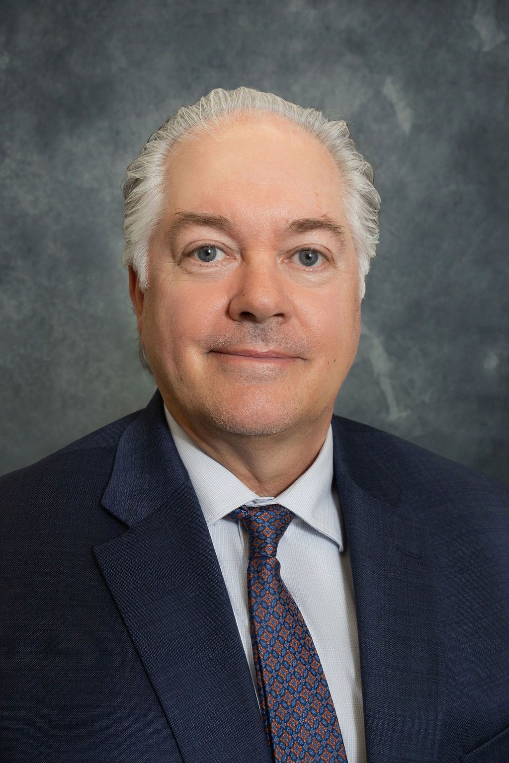 A man in a suit and tie is smiling for the camera.