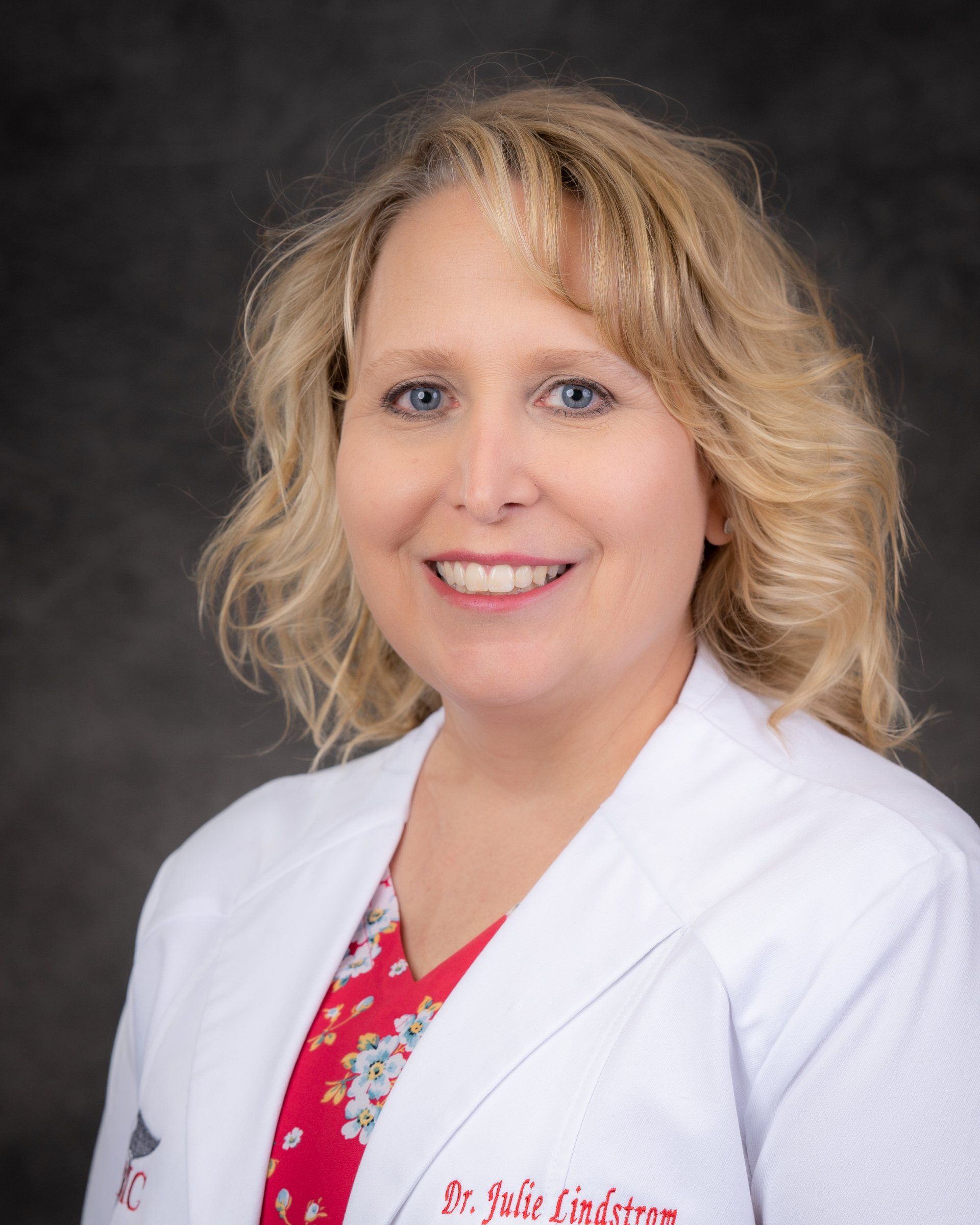 A woman in a white lab coat is smiling for the camera.