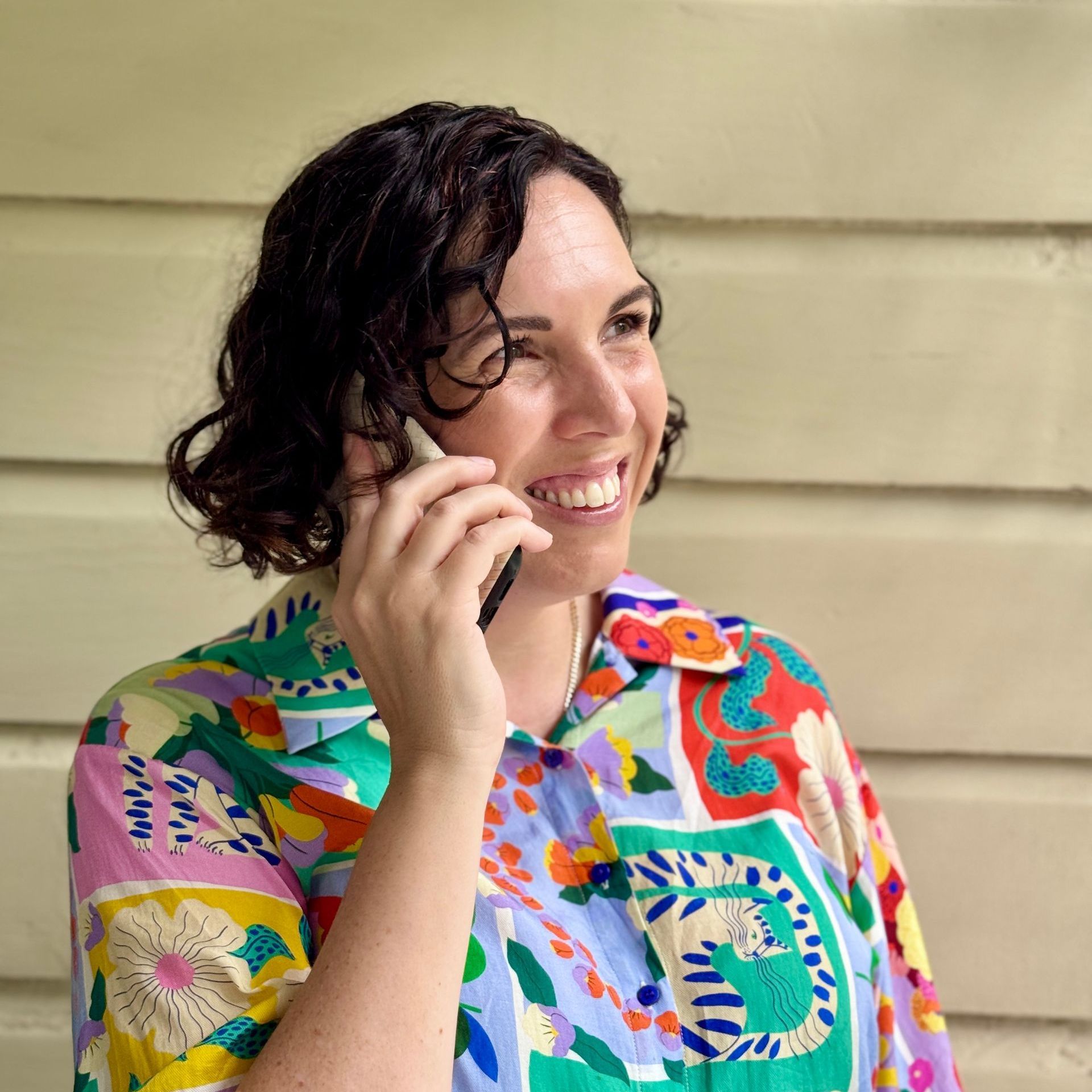 Sarah Dummer in a colourful shirt is talking on a mobile phone.