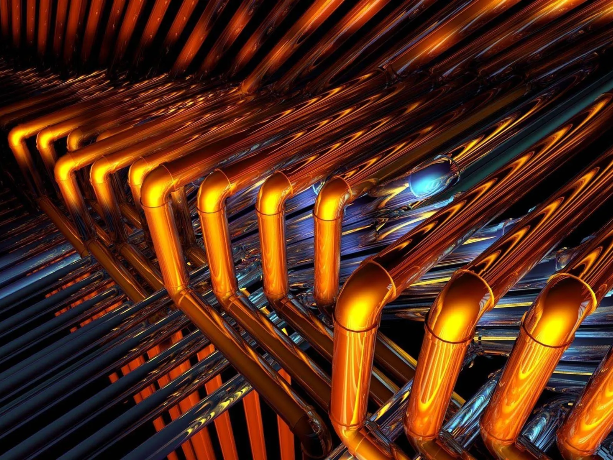 Close-up view of intricate copper pipes with a warm, orange glow.