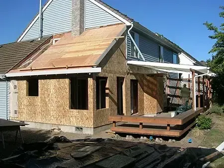 Partially built house with exposed plywood siding and a small deck under construction outdoors