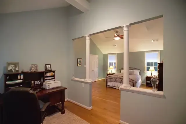 Home office overlooking a living room with hardwood floors and light blue walls.