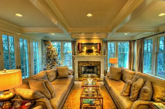 Luxurious living room with two sofas, a fireplace, and large windows overlooking trees