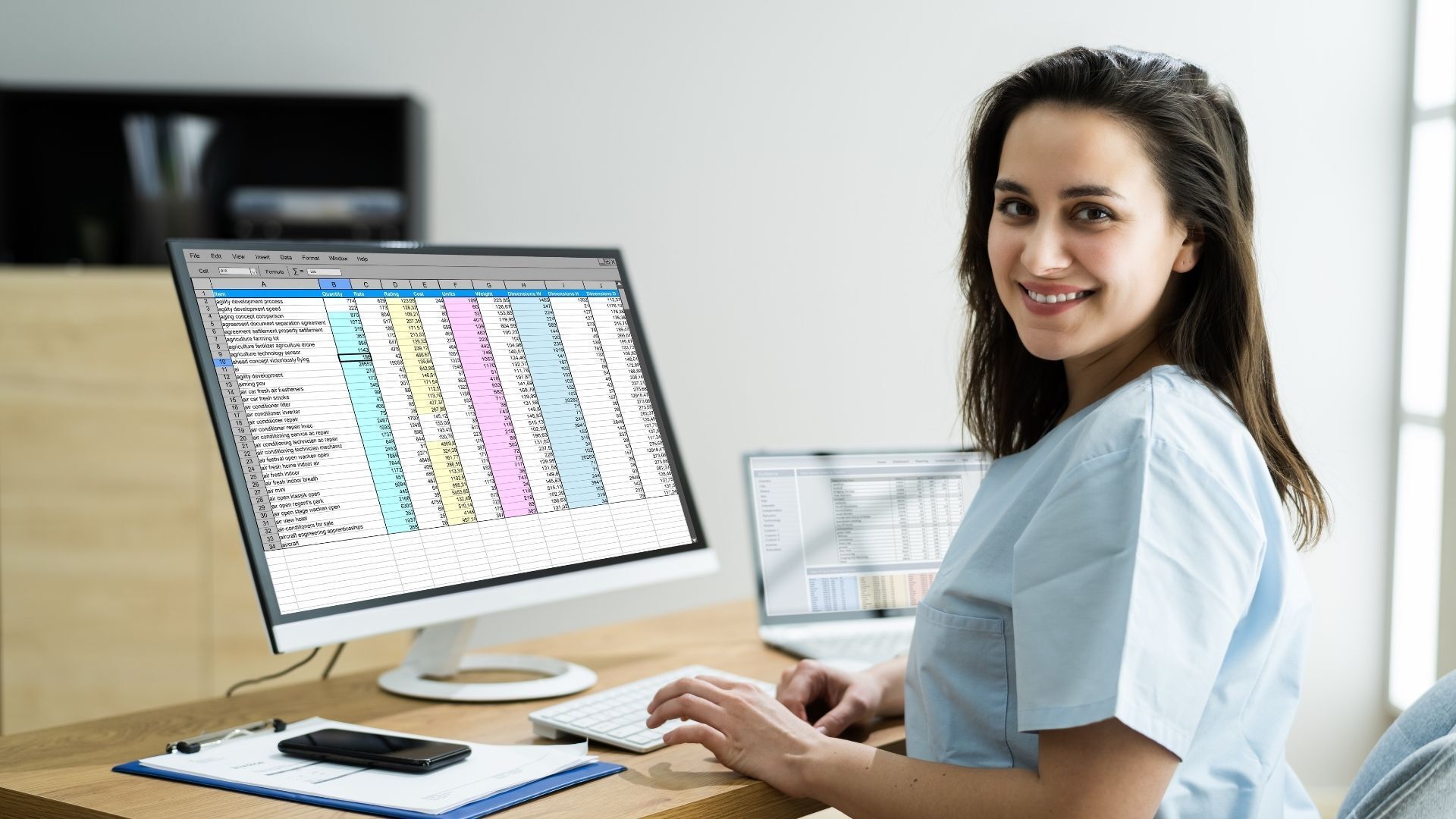 Eine Krankenschwester sitzt an einem Schreibtisch vor einem Computer.