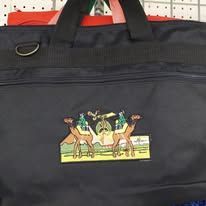 Black duffel bag with a colorful horse rider logo on the front, hanging on a pegboard wall.