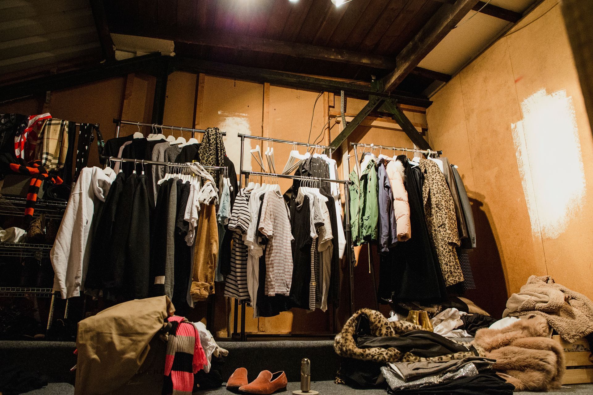 Clothing racks and folded garments in a dimly lit shop or market stall