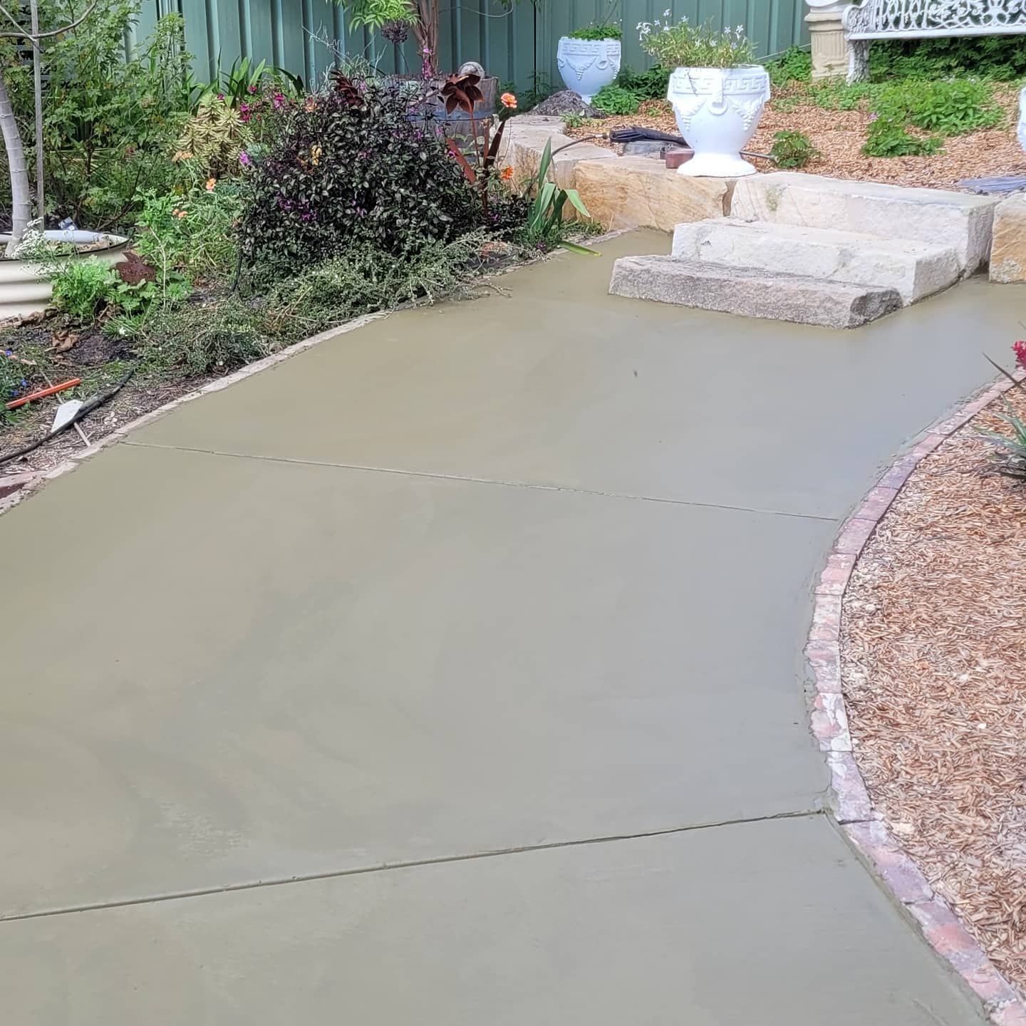 A Concrete Walkway Leading To A Garden With A Fence In The Background — Dave Smith Concrete in Port Stephens, NSW