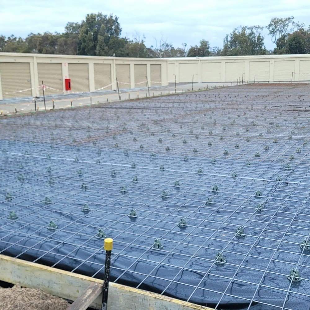 A Large Concrete Foundation With Buildings In The Background — Dave Smith Concrete in Newcastle, NSW