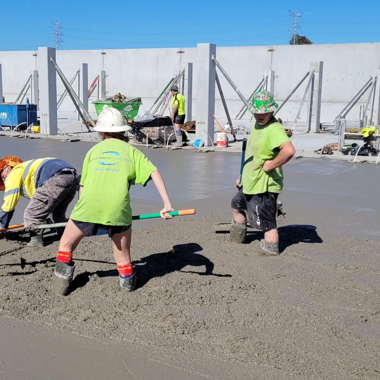 A Group Of Construction Workers Are Working On A Concrete Floor — Dave Smith Concrete in Salt Ash, NSW