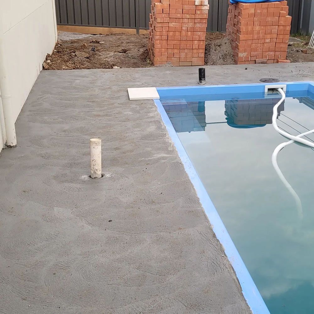 A Swimming Pool With a Brick Wall Behind It — Dave Smith Concrete in Salt Ash, NSW