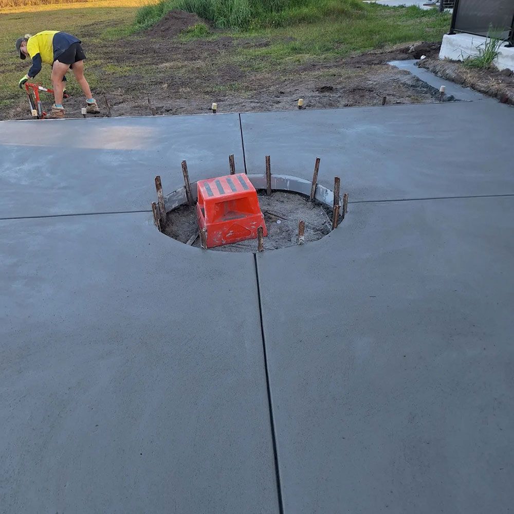 A Man is Working on a Concrete Driveway With an Orange Box in the Middle — Dave Smith Concrete in Salt Ash, NSW
