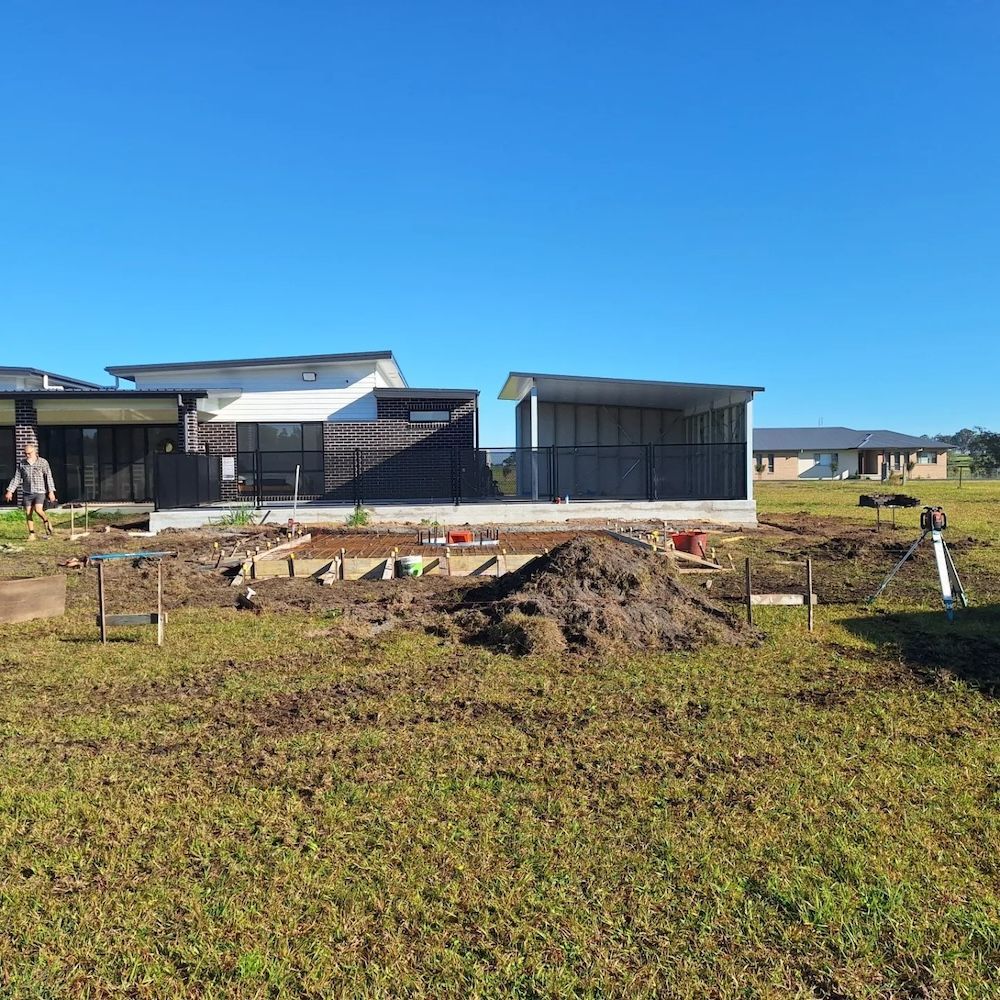 A Concrete Walkway is Being Built in Front of a House — Dave Smith Concrete in Central Coast, NSW