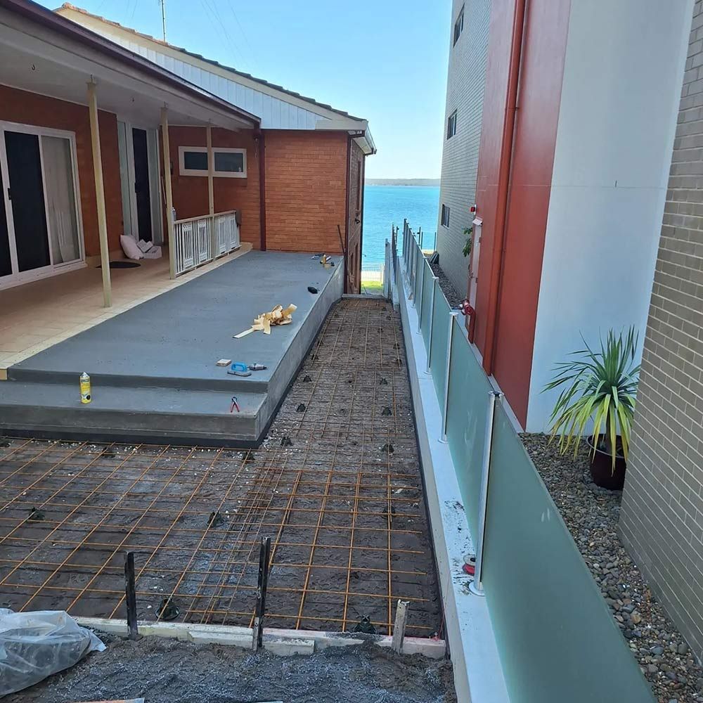 A Concrete Walkway is Being Built Between Two Buildings Next to the Ocean — Dave Smith Concrete in Lemon Tree Passage, NSW
