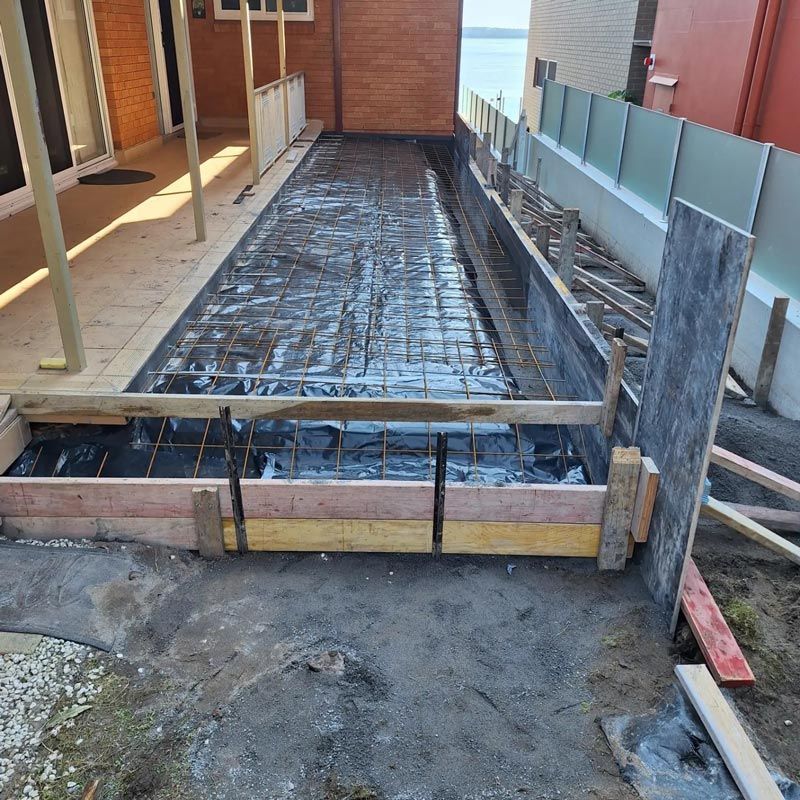 A Concrete Walkway is Being Built in Front of a House — Dave Smith Concrete in Salt Ash, NSW