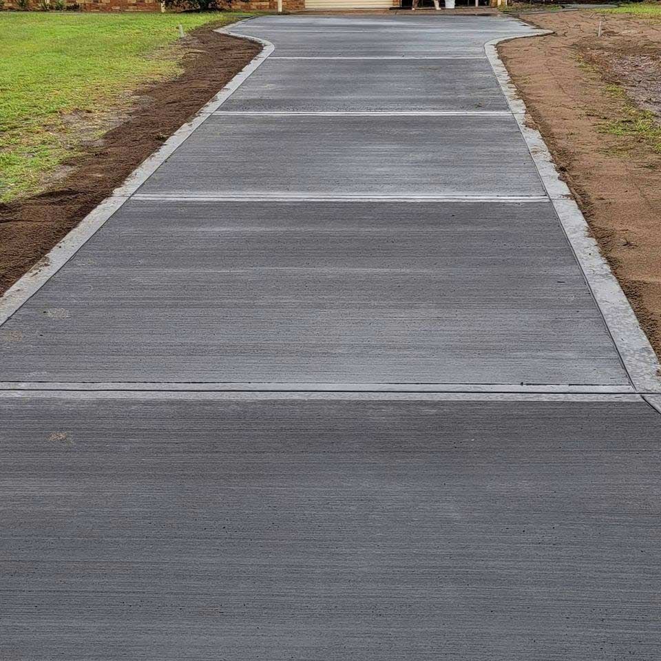 A Concrete Driveway Leading to a House With Grass on the Side — Dave Smith Concrete in Central Coast, NSW