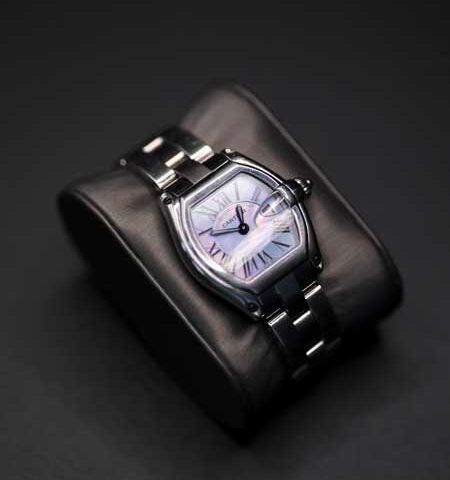Silver wristwatch with a square face resting on a black leather cushion