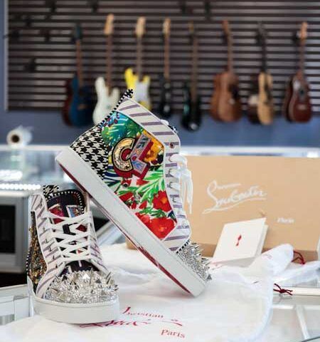 Colorful high-top sneakers displayed in a guitar shop, with guitars hanging in the background.