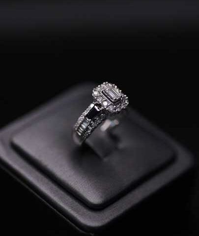 Silver diamond ring on a black display stand against a dark background