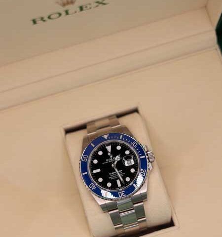 Rolex watch with blue bezel in a beige presentation box