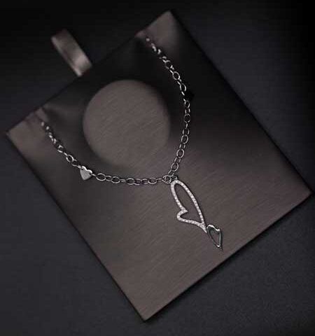 Black jewelry box with a silver chain necklace and heart-shaped pendant on a dark background