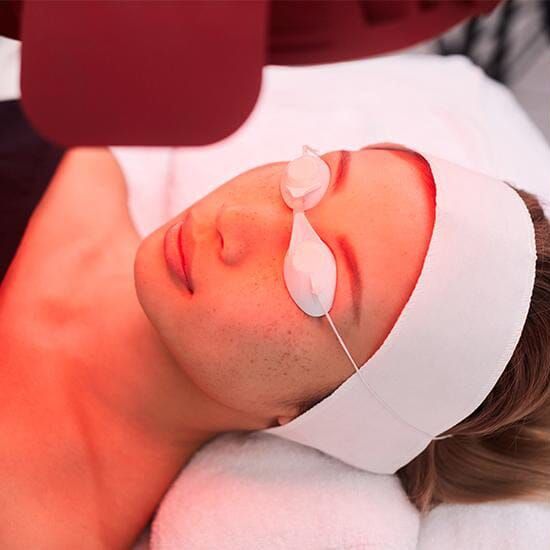 Woman lying on a treatment bed with eye pads and a headband during a spa facial treatment