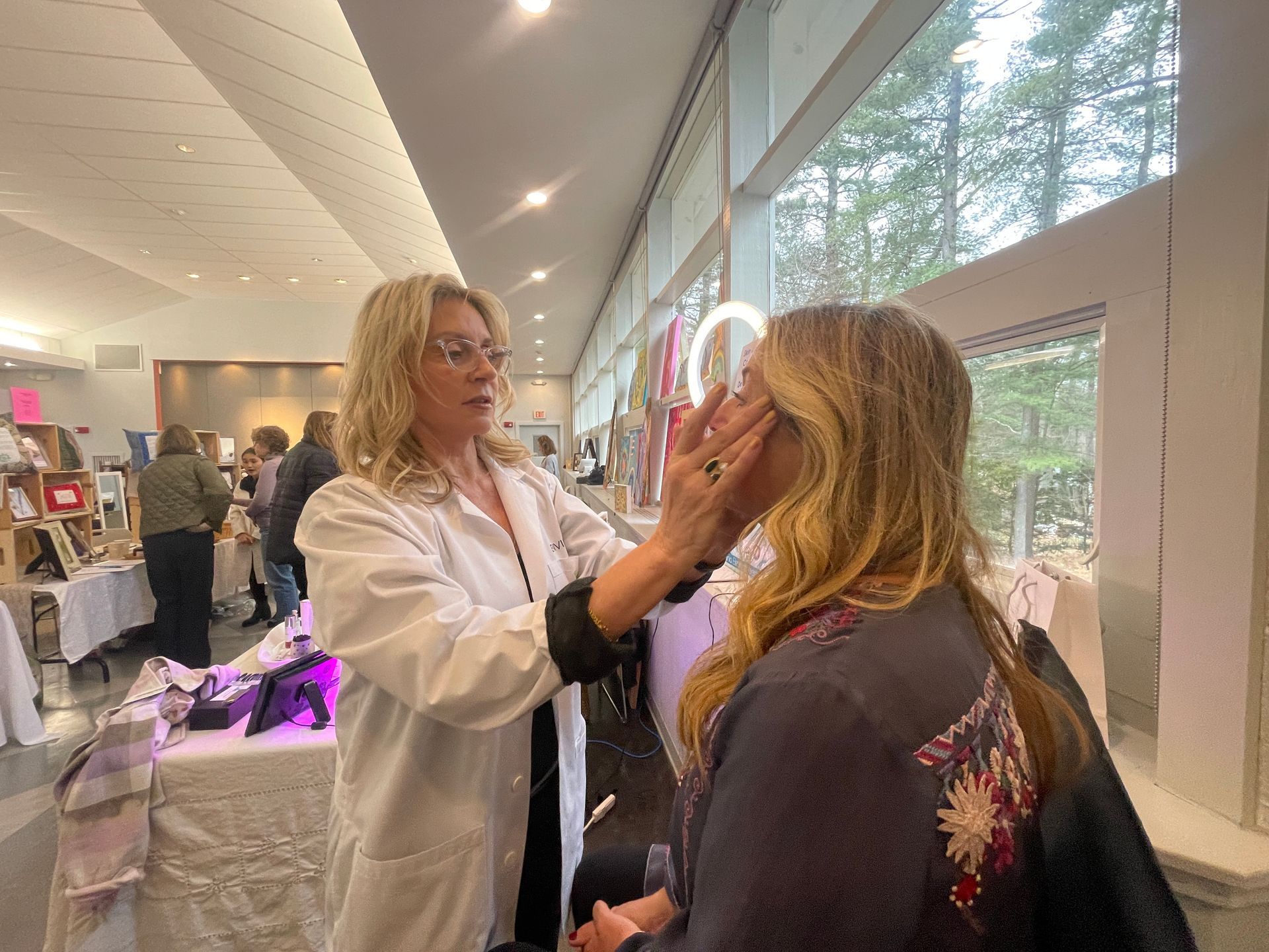 Optometrist adjusting a patient’s glasses in a bright clinic hallway