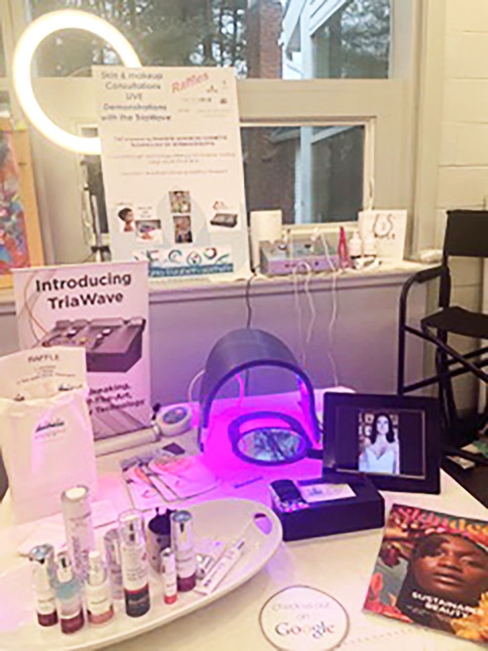 Trade show display for “TriaWave” with pink-lit skincare products, brochures, and a tablet on a table