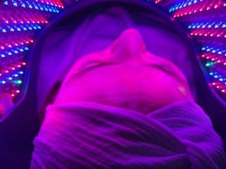 Close-up of a face under purple neon lights with a hood and scarf covering the lower half