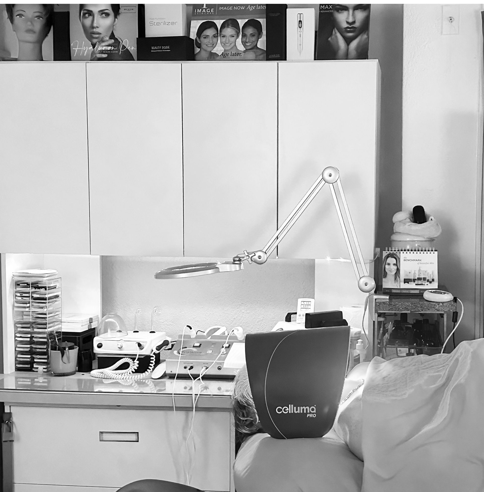 Desk with lamp, chair, cabinet doors, and a shelf of photos in a small room.