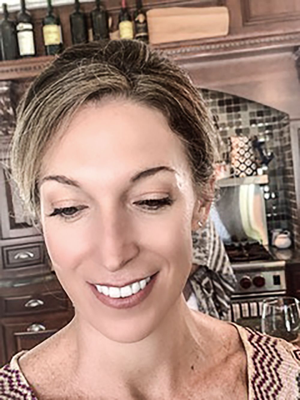 Smiling person in a kitchen, with a stove and cabinets in the background
