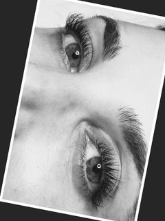Black-and-white close-up of two eyes and eyebrows on a tilted portrait crop