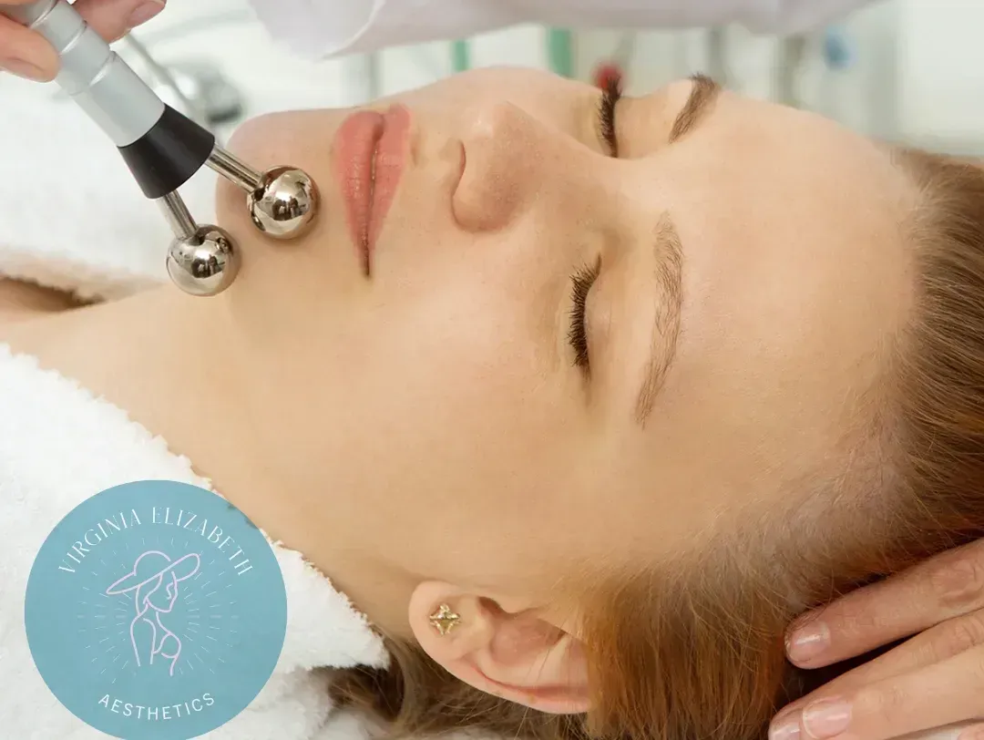A person receiving a microcurrent facial treatment with a dual-probe device applied to their jawline.