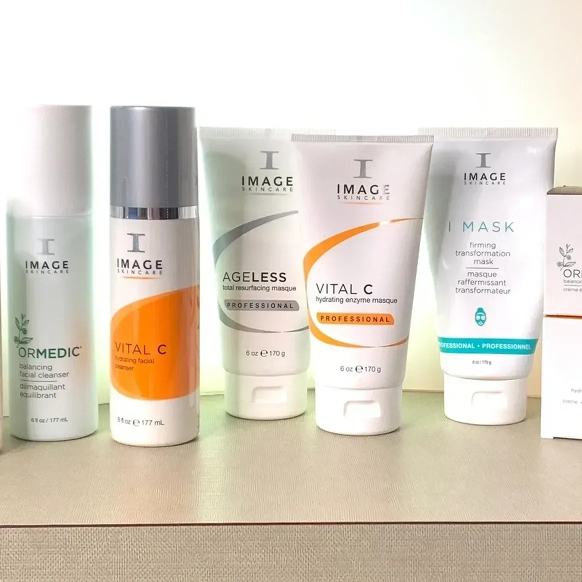 A collection of IMAGE Skincare bottles and tubes arranged in a row on a light-colored surface.
