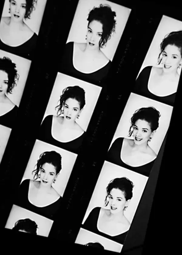 A contact sheet of black-and-white headshots featuring a person with curly hair wearing a dark scoop-neck shirt.