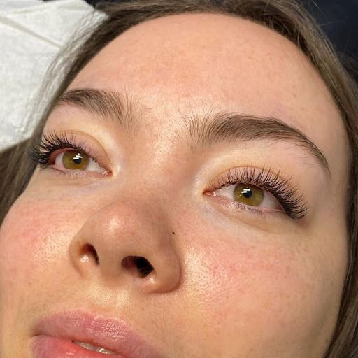 Close-up of a face with green eyes, long lashes, and natural makeup in warm sunlight