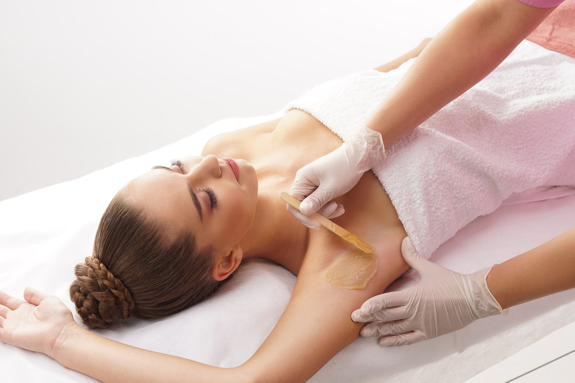 A professional uses a laser hair removal device on a person's lower leg in a clinic setting.