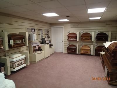 Showroom with rows of colorful coffins and caskets under fluorescent lights
